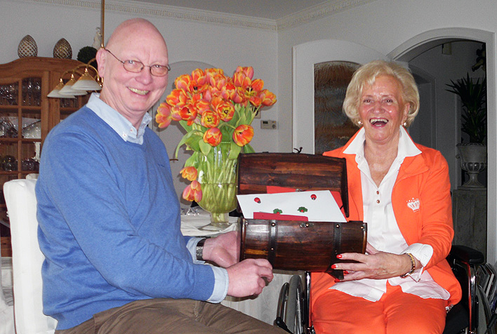 Irene Stelberg (r.) bergibt Michael Adomaitis von der Johannes-Hospiz Oberberg Stiftung ihre Geburtstagsgeschenke in einer Schatztruhe