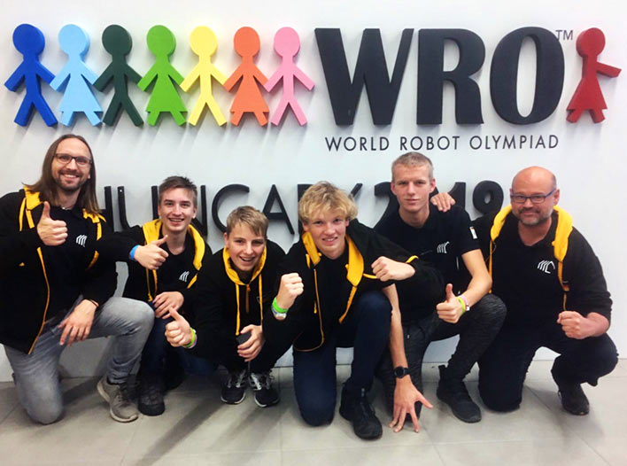 Teamfoto vor World-Robot-Olympiad-Logo