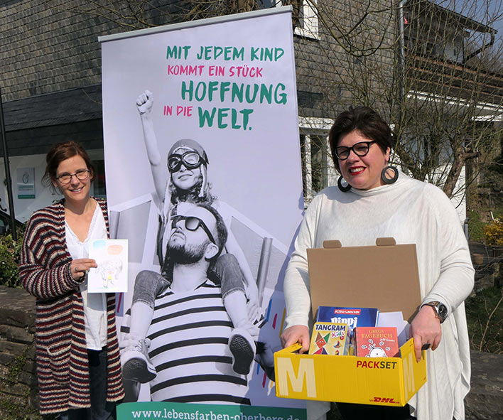 Martina Gramm und Sandra Karsten (r.) vor der Geschäftsstelle in Wiehl mit einem der Pakete, die gerade bei den Familien eintrudeln. Foto: Verein Lebensfarben