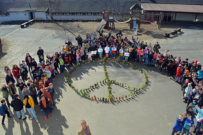 Um das aus Frhblhern zusammengesetzte Friedenszeichen gruppierten sich Schlerinnen und Schler der Grundschule in Wiehl. Foto: Foto: GVB Wiehl